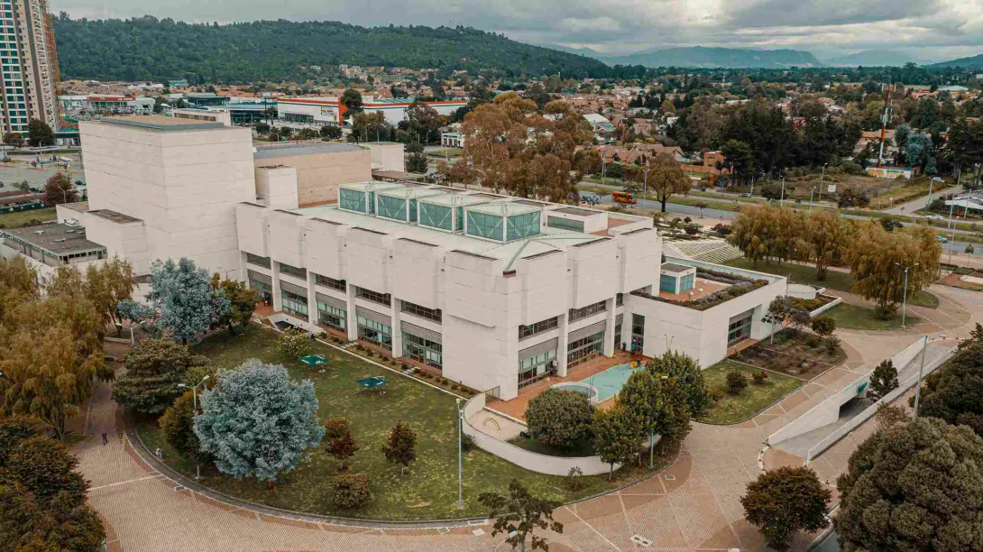Large, two-story brick and white concrete building, surrounded by green areas.