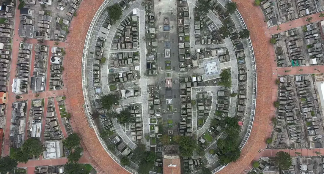 Vista aérea desde un dron hacia abajo en el que se observa una panorámica circular del cementerio central. Se destacan caminos en ladrillo, estilo laberinto, y algunos árboles.