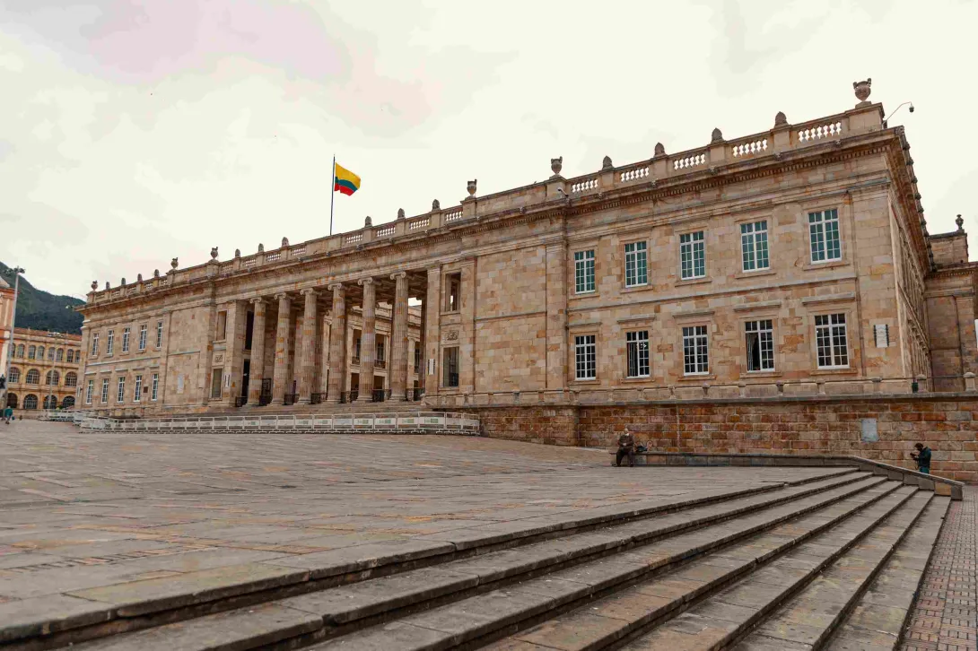 Fachada del Capitolio Nacional en piedra. Se observan algunas ventanas y la bandera de Colombia izada en lo alto.