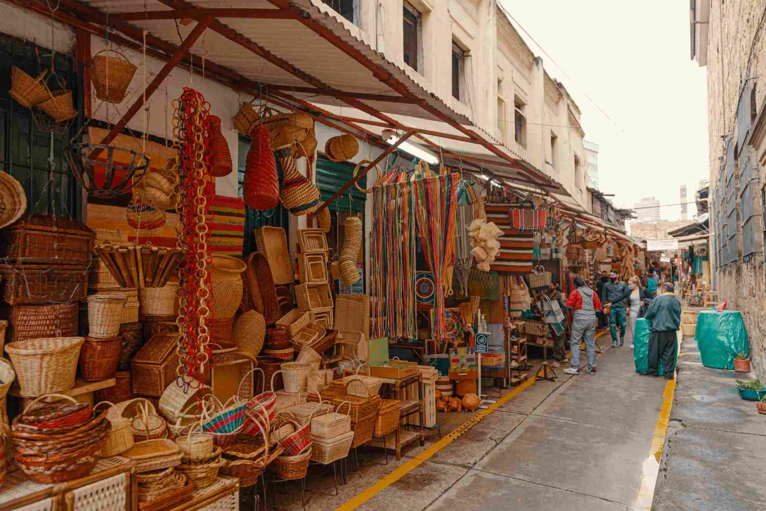 Panoramica de calle repleta de coloridos artículos artesanales como canastos y hamacas.
