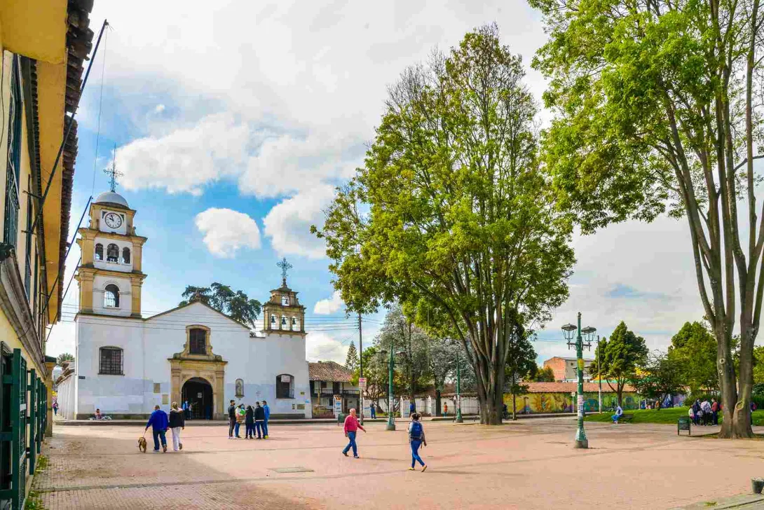 Plano general de la plaza de Fontibón en la que se observa la iglesia y una gran plazoleta al frente con personas y árboles.