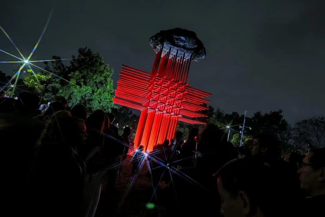  Una gran cruz roja iluminada en la noche, destacando en el cielo oscuro.