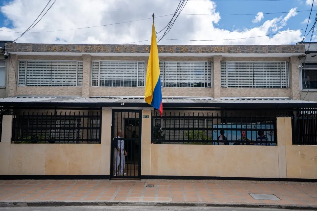 Fachada de la Casa de Historia Naval Armada de Colombia, un edificio de dos niveles con ventanas amplias protegidas por rejas. En el centro ondea una bandera de Colombia frente a la entrada principal, que está cerrada con una reja negra.