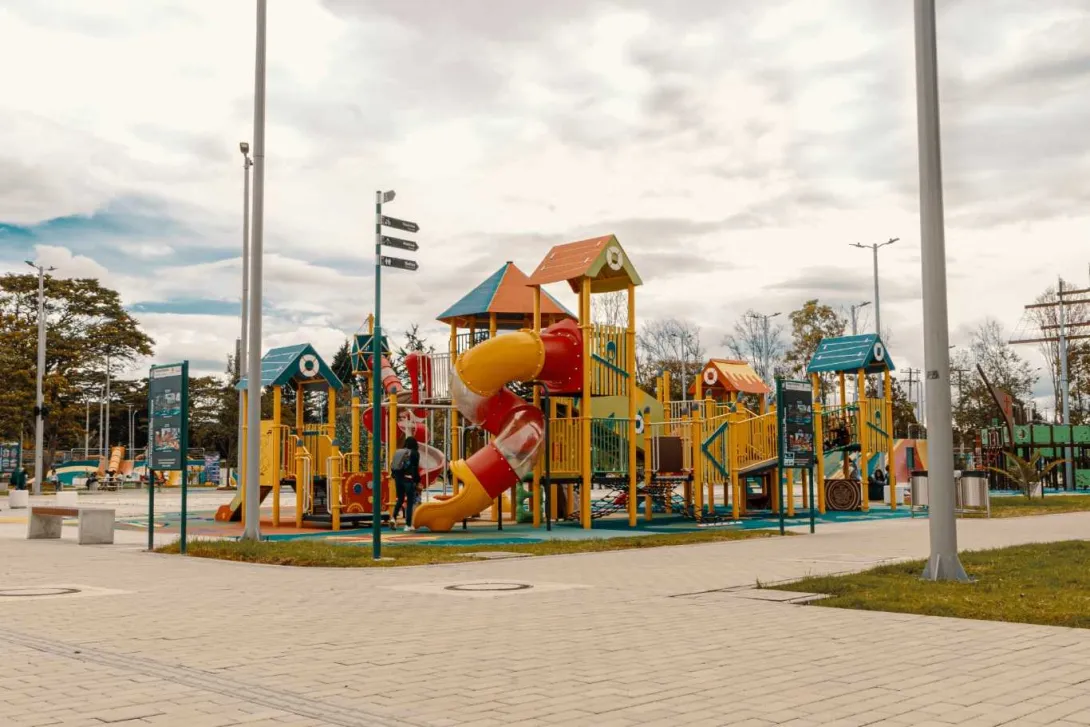  Un parque infantil con un tobogán colorido y un conjunto de juegos para niños.    
