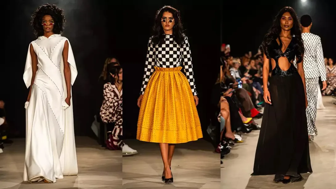 Tres modelos desfilan en pasarela con atuendos llamativos: vestido blanco, conjunto de falda amarilla con top a cuadros y vestido negro elegante.