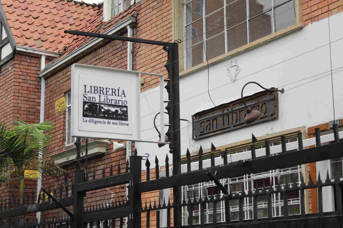 Fachada de la librería San Librario con letrero colgante en una calle de ladrillo.