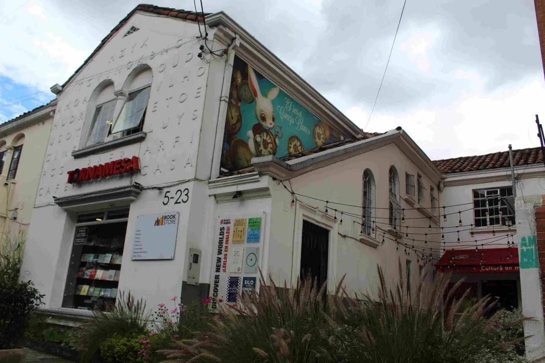 Fachada de la librería Tornamesa, edificio blanco con murales, carteles de libros y entrada visible desde la calle.