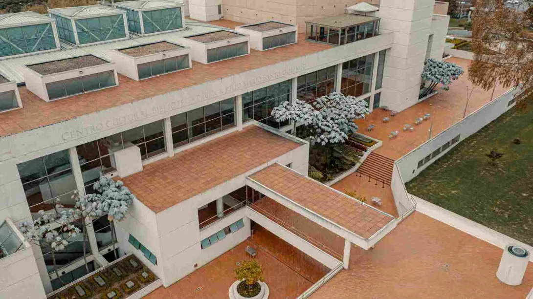 Aerial view of a modern cultural center with brick terraces, large windows, and surrounding green spaces.