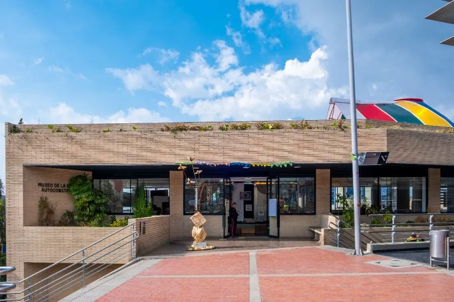 Fachada del Museo de la Ciudad Autoconstruida, edificio de ladrillo con entrada principal, rampas y cielo despejado.
