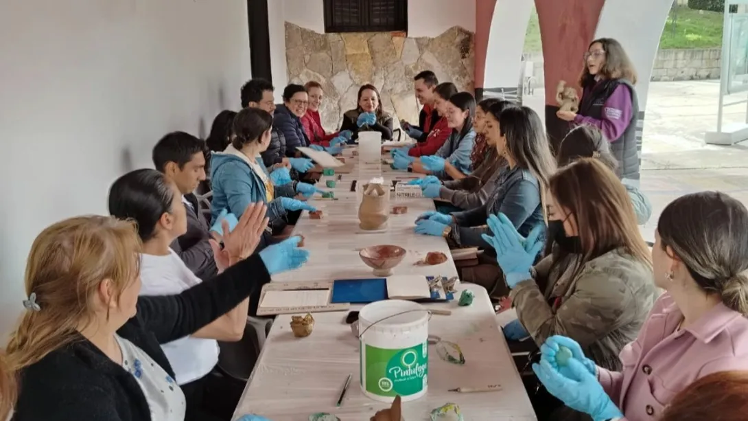  Un grupo de personas sentadas a una mesa, todas usando guantes, conversando y compartiendo ideas.