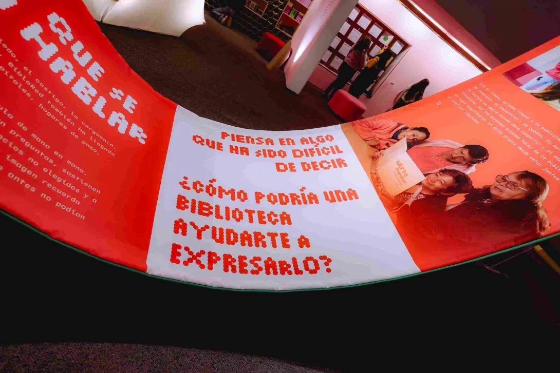 An interactive installation featuring messages about the power of libraries and personal expression, displayed in a space illuminated with warm red and orange tones during a cultural showcase.