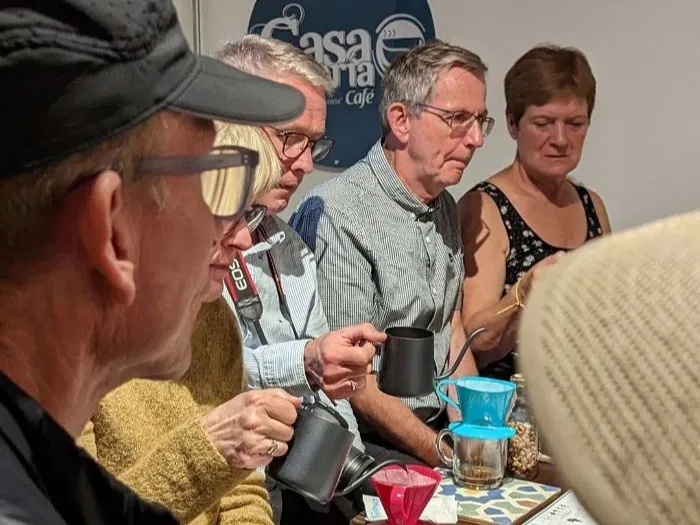 Grupo de visitantes participa en una experiencia de cata de café en Casa Galería Café, observando y degustando distintas preparaciones mientras conocen sobre el origen, los aromas y los sabores del café colombiano.