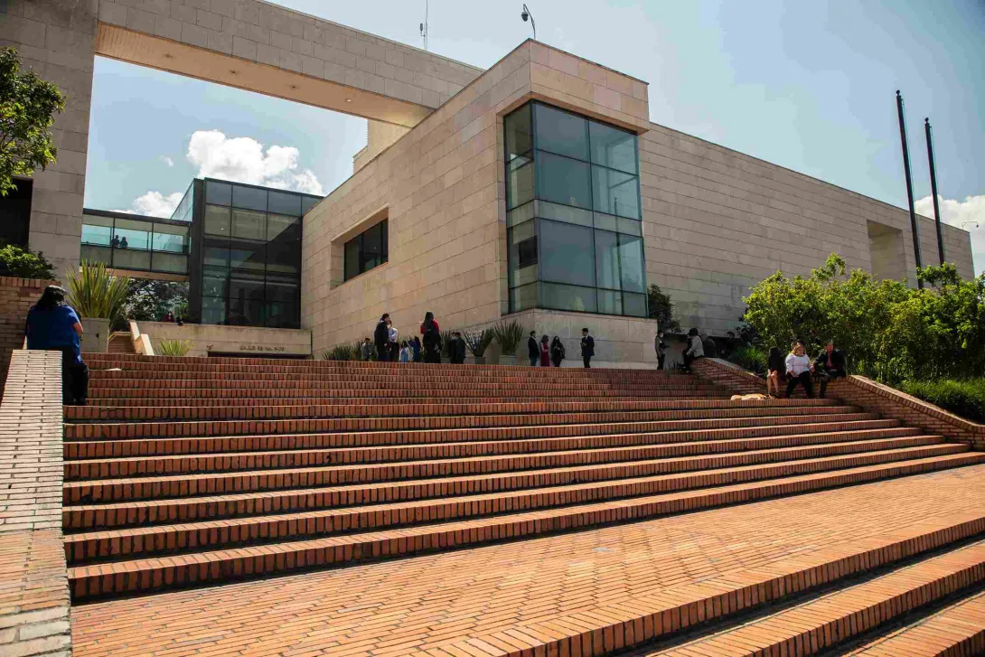 Vista frontal del Archivo de Bogotá, con amplias escalinatas de ladrillo, jardines y una moderna fachada de piedra y vidrio.
