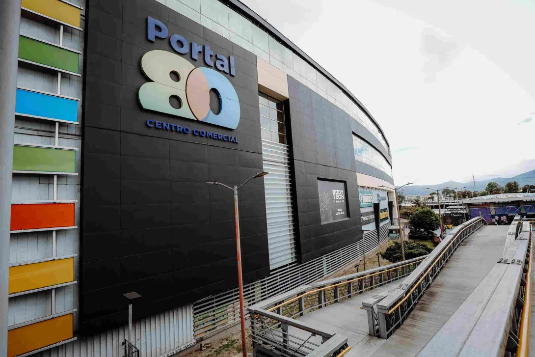 La imponente fachada de Portal 80 destaca por su diseño contemporáneo y sus llamativos detalles de color. Sus amplios accesos y pasarelas reflejan el carácter moderno de uno de los principales puntos de encuentro del occidente de Bogotá.