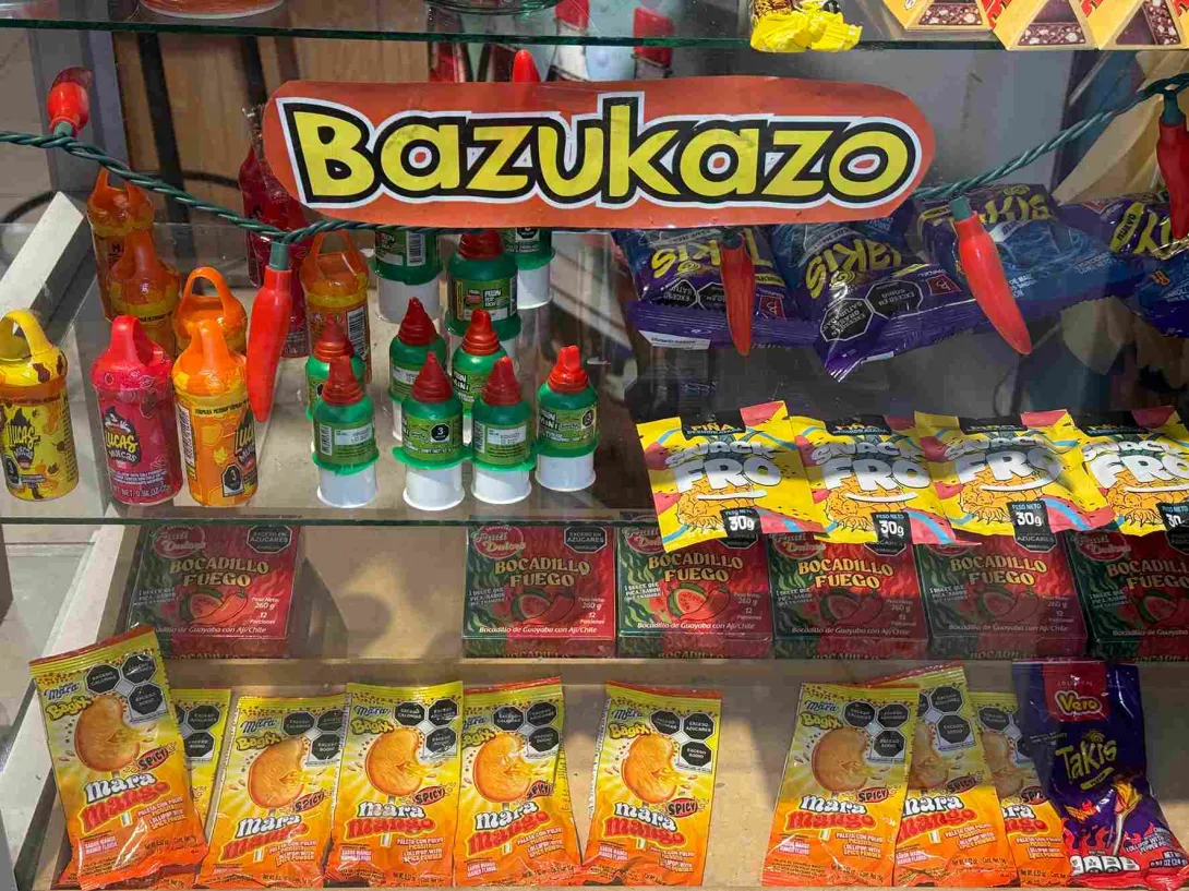 Exhibición de dulces, botanas y productos mexicanos en una vitrina identificada como Bazukazo.