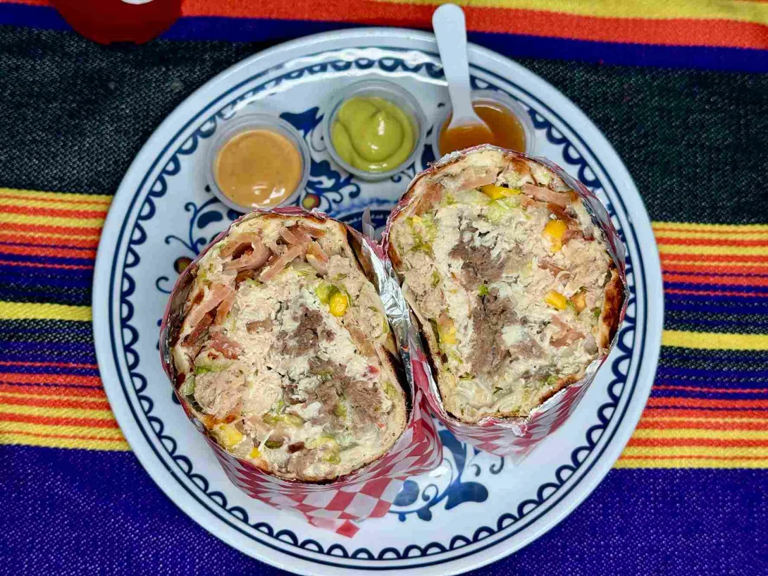 Burritos de Antojos Mexicanos servidos en papel decorativo, acompañados de tres salsas.