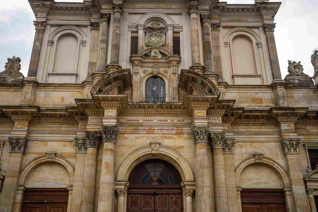 Detalle de la fachada de la Iglesia del Voto Nacional, donde sobresalen sus columnas ornamentadas, arcos, relieves y elementos escultóricos que resaltan la riqueza arquitectónica del templo.
