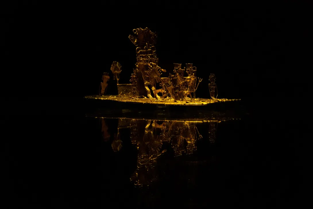 El Museo del Oro exhibe una pieza precolombina de oro, iluminada sobre un fondo oscuro que resalta sus detalles y brillo.