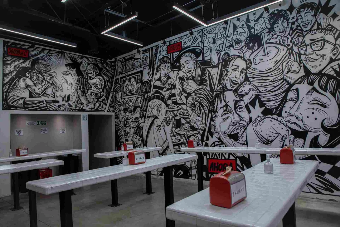 Interior de Los Tacos Norteños con mural de temática mexicana y mesas para comensales.