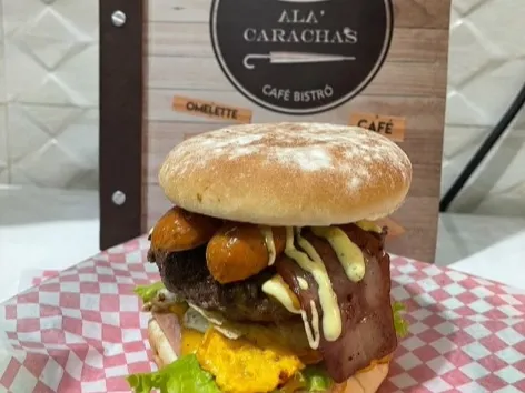 Foto1: Hamburguesa artesanal de Ála' Carachas, servida con carne, queso, vegetales y salsas en un pan artesanal.