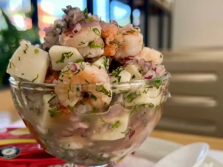 Ceviche de camarones y pescado con cebolla morada, cilantro y limón, servido en una copa de vidrio.