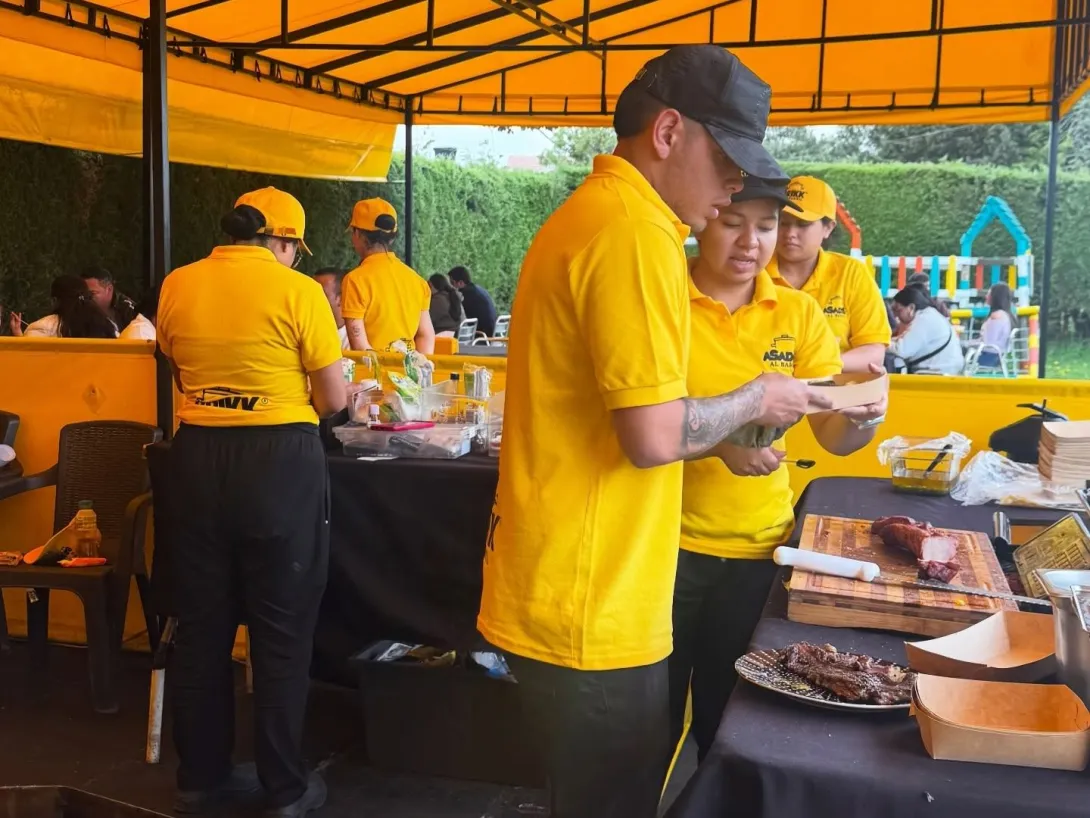 Personal de Asados al Barril prepara y sirve carnes a la parrilla en un ambiente al aire libre, con cortes listos para disfrutar.