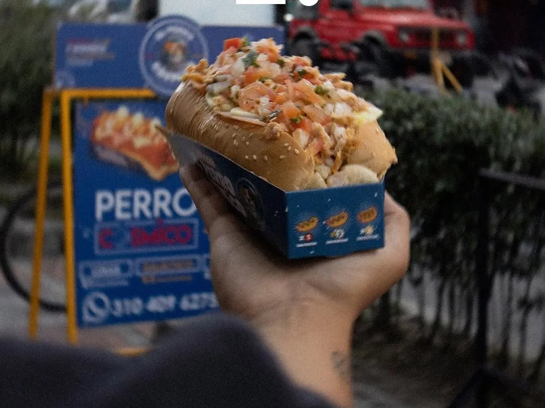 Perro caliente cargado de toppings y servido para llevar.
