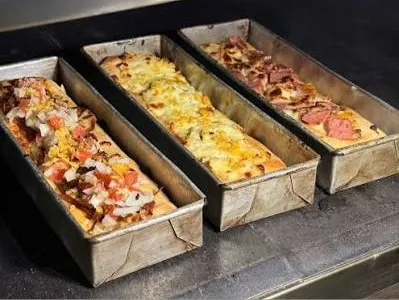 Pizzas de masa madre con diferentes ingredientes y coberturas, listas para hornear.