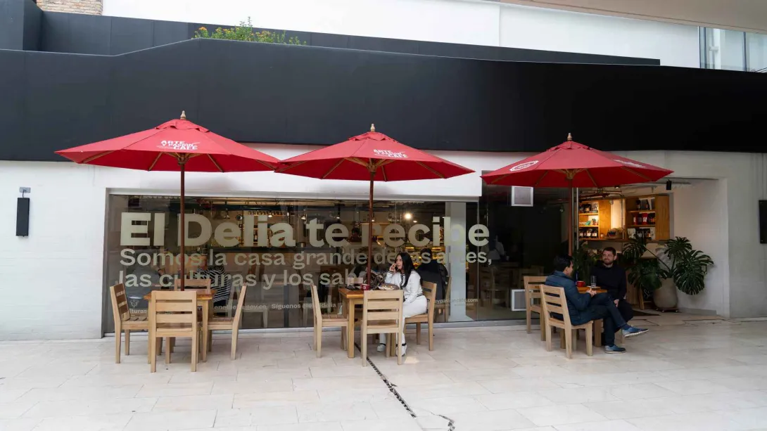 Terraza exterior con sombrillas rojas de Arte y Pasión Café, mesas de madera y clientes compartiendo afuera. 