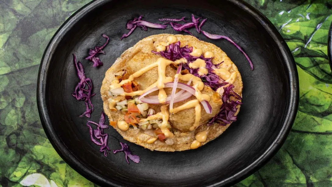 La perfección en una tostada. Pollo, maíz, salsa cremosa y col morada. Sabor y arte en un solo plato.