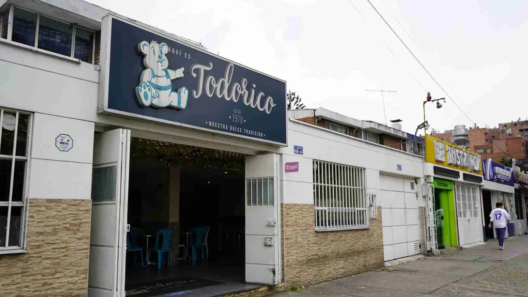 Fachada exterior de la repostería Todorico con aviso azul, oso de logo y puertas abiertas a la calle. 
