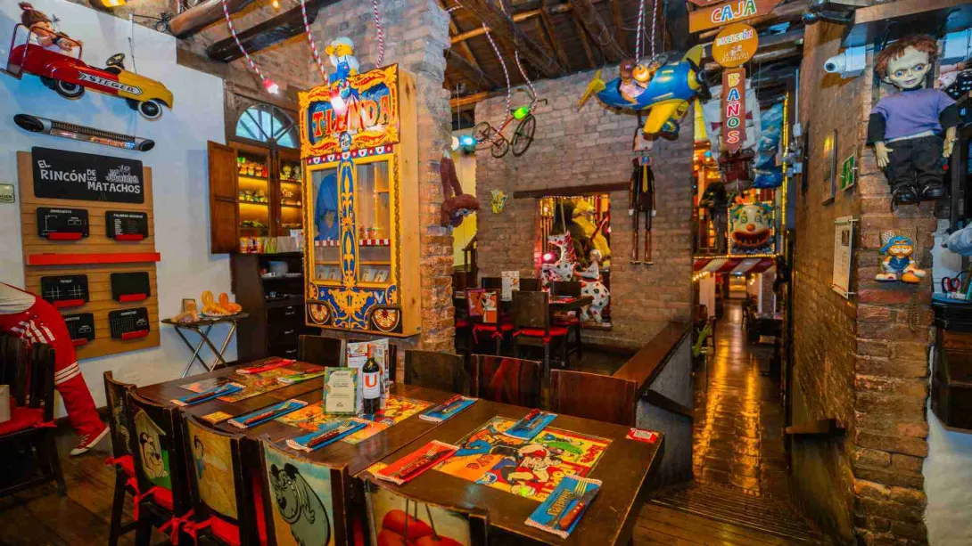  Salón temático con muñecos de colección, carritos y juguetes retro colgando del techo sobre las mesas servidas.