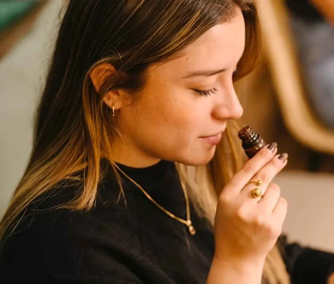 Mujer oliendo un frasco de aroma durante una cata sensorial en el taller de Legado Cacao. 