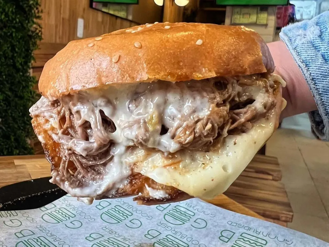 Hamburguesa de pulled pork con abundante queso y salsa, servida en Good Burger.
