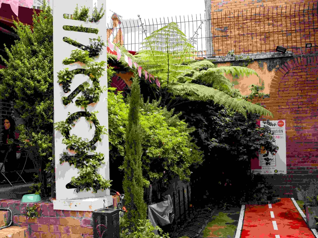  Jardín interior de Moovil, con vegetación, muros de ladrillo y un circuito que evoca la experiencia de pedalear por Bogotá.