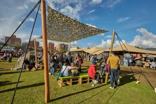 Público disfruta de la oferta gastronómica y cultural de un festival al aire libre en un parque.