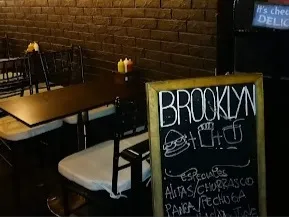 Interior de Brooklyng, con mesas y una pizarra que anuncia sus especialidades.
