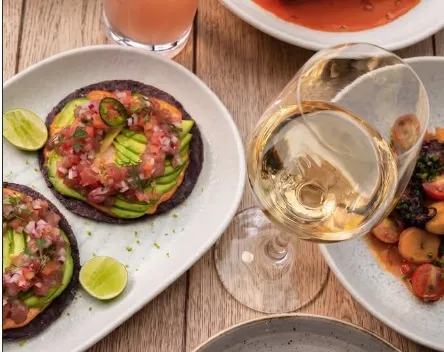 Tostadas de aguacate con pico de gallo y limón, acompañadas de una copa de vino blanco en 80 Sillas.