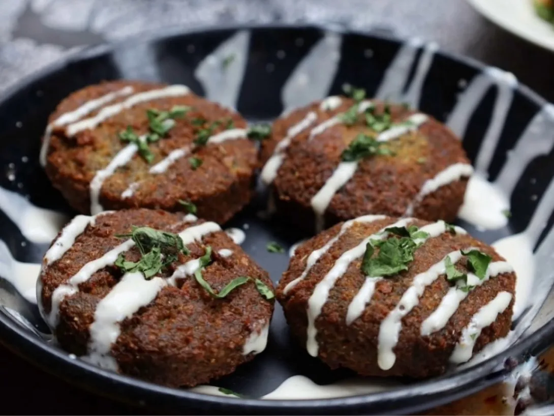 Croquetas de kibbeh servidas con salsa de yogur y hierbas frescas.