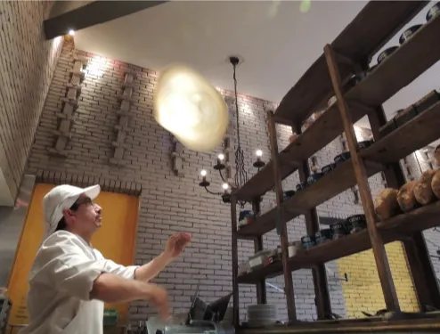 Chef preparando una masa artesanal en el interior de Café Amarti, junto a estanterías con productos e ingredientes.