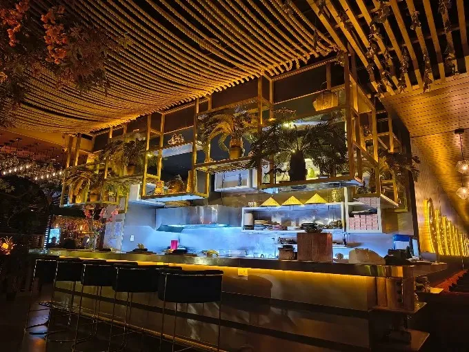 Interior de Seratta Gourmand Market con barra abierta, cocina a la vista, iluminación cálida y decoración sofisticada.