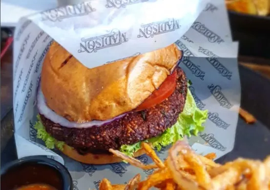 Hamburguesa artesanal con carne, lechuga, tomate y cebolla, acompañada de aros de cebolla y salsa.